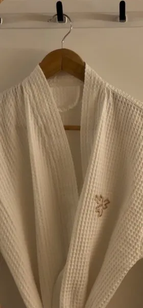 A white waffle robe with the OG logo on a wooden hanger