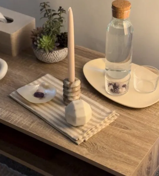 A side table with a carafe of water, a candle and succulents