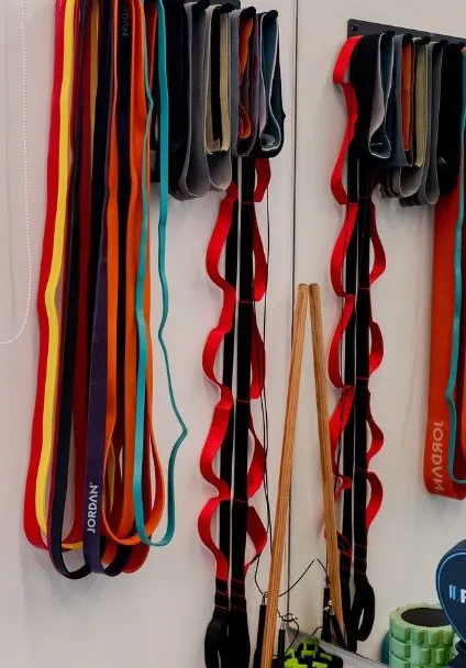 Resistance bands, a foam roller and Precor dumbbells on a wall rack