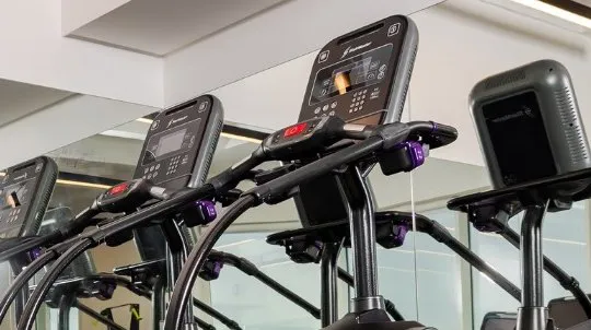 A row of StairMasters beside a mirrored wall