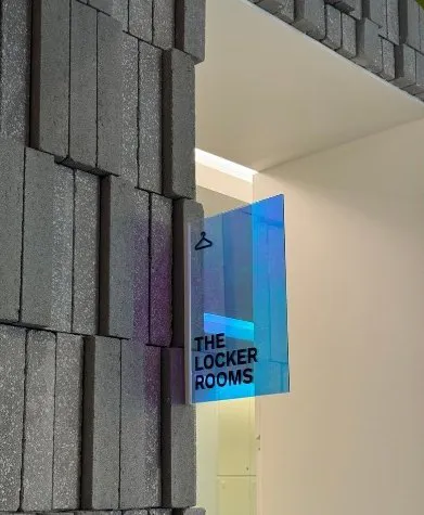 Textured grey brick wall and the holographic sign for the locker rooms